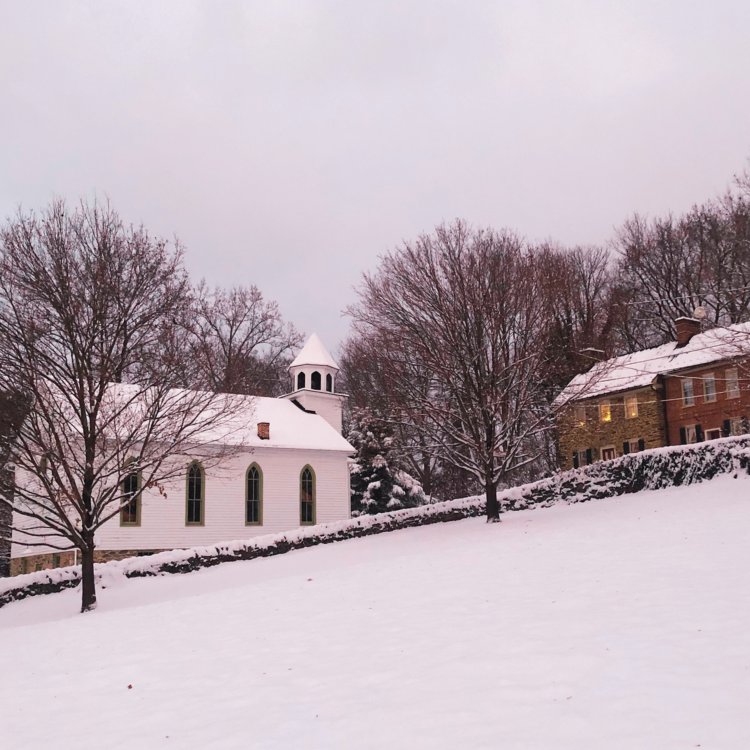 A snowy hill in front of a snow covered white frame church